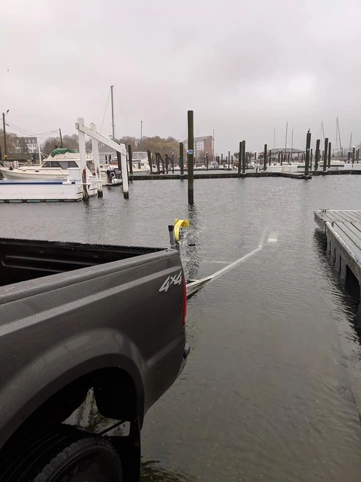 Nazareth Marine truck backing a boat trailer down a flooded marina ramp on Narragansett Bay