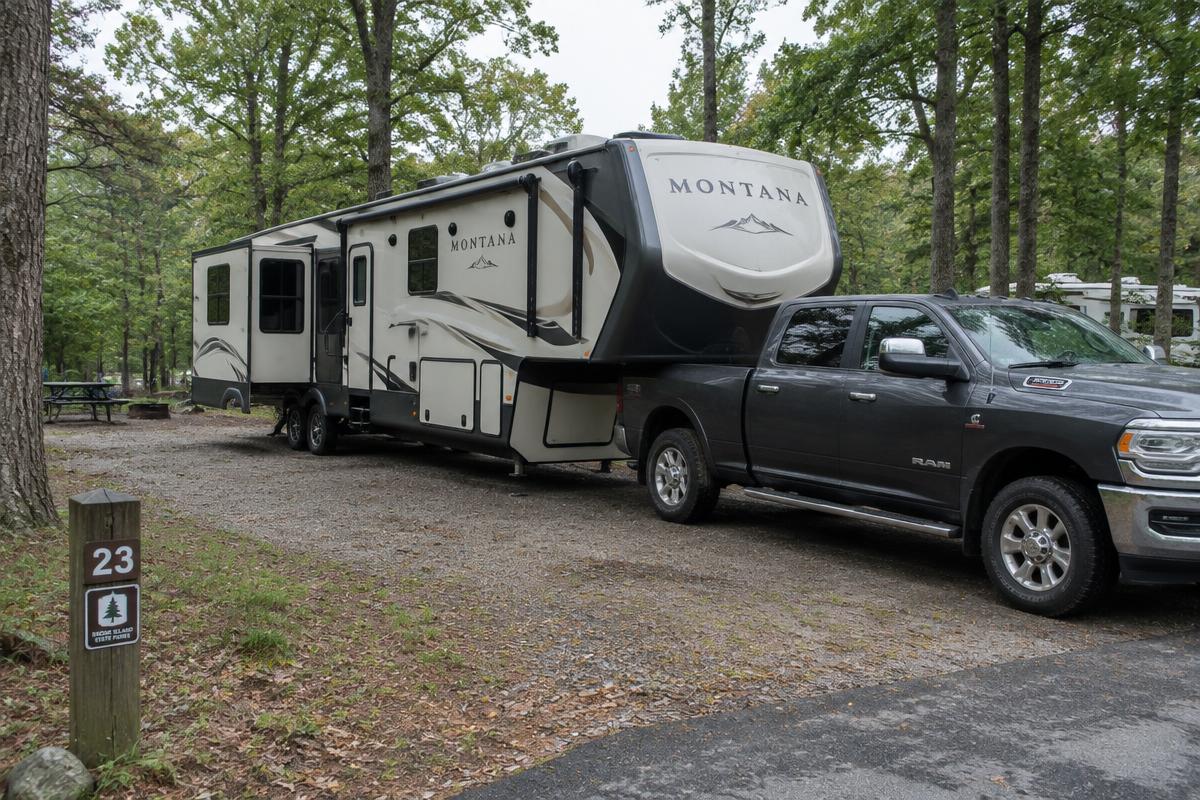 Fifth-wheel camper hitched to a pickup truck at a wooded Rhode Island campsite