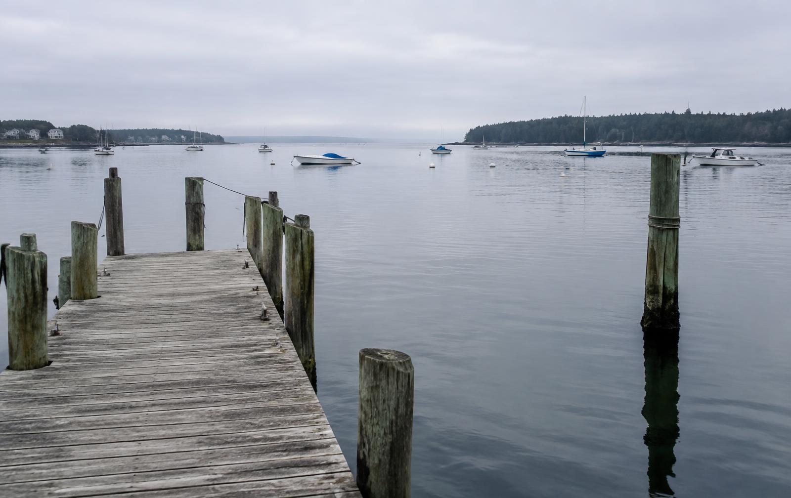 Weathered wooden dock and pilings on a calm New England harbor